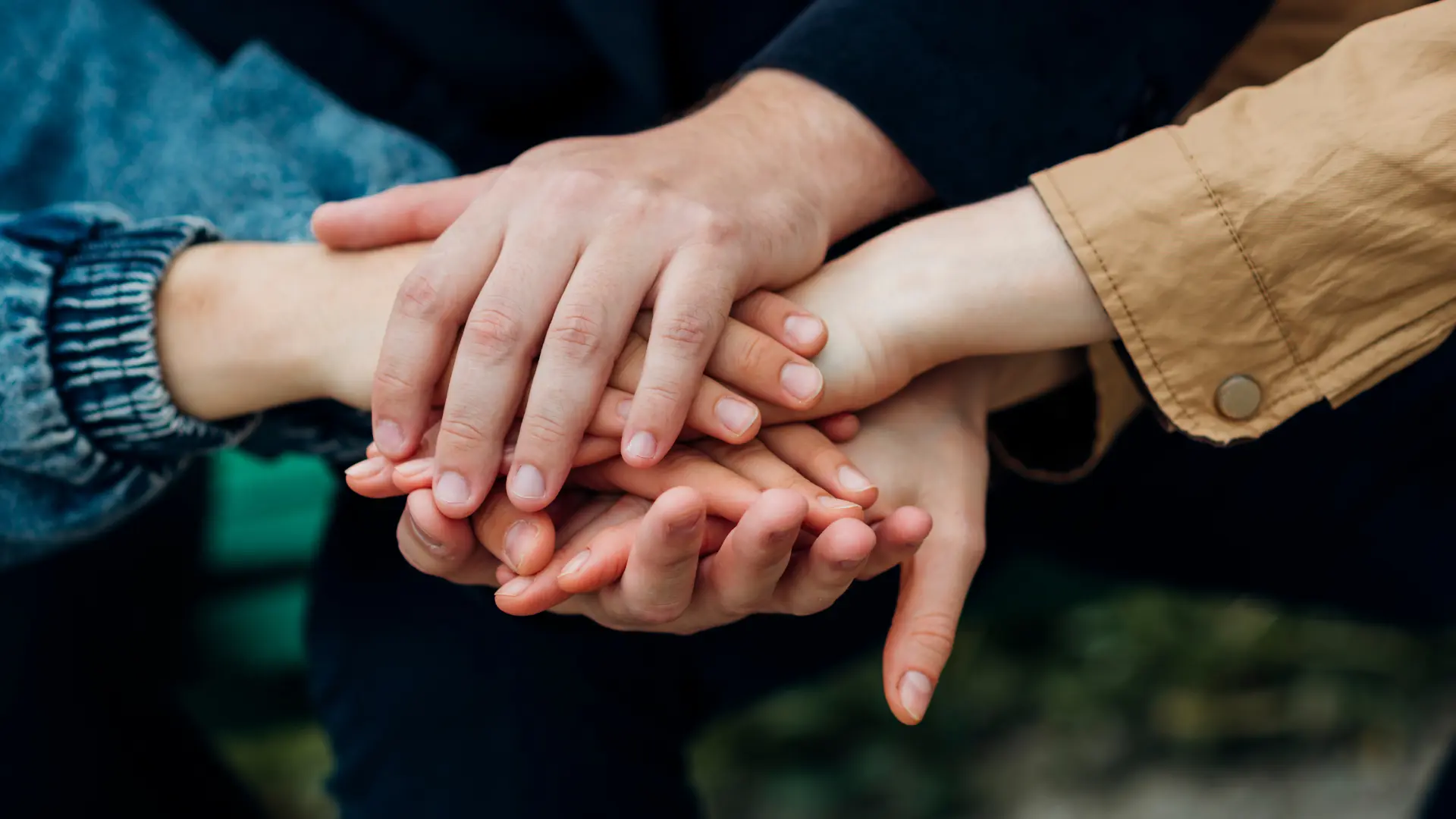 părinți și adolescent care pun mâinile unele peste altele pentru a semnifica că rămân o echipă chiar și după divorț